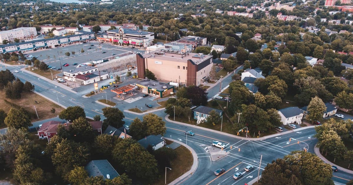 Aerial photo capturing a suburban road intersection with buildings and lush greenery.