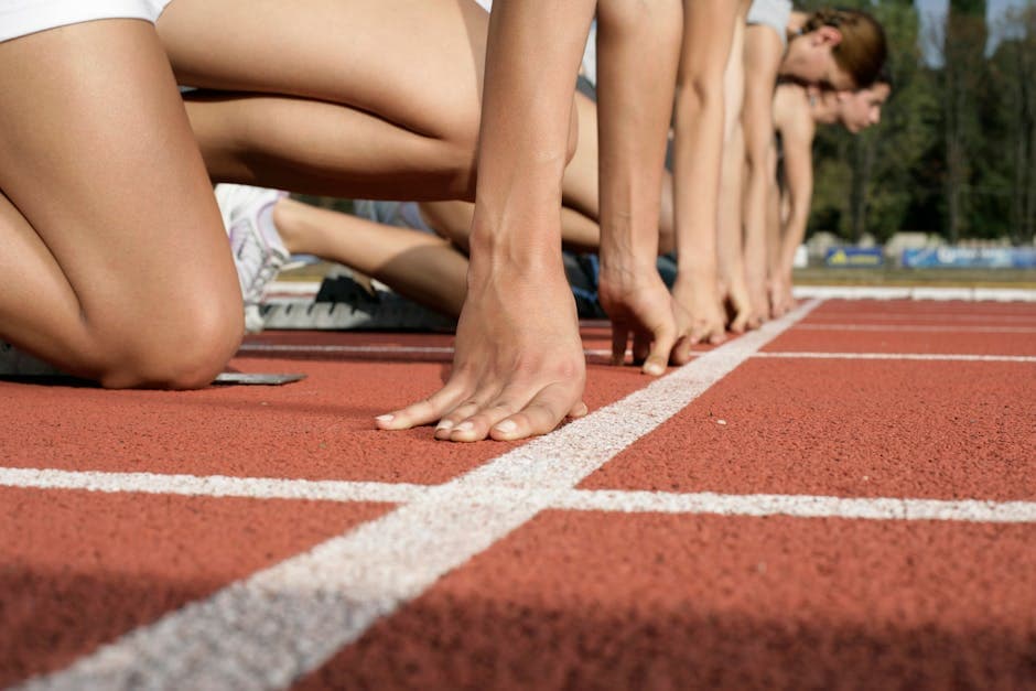 Close-up of runners at the starting line ready to race on a track field.